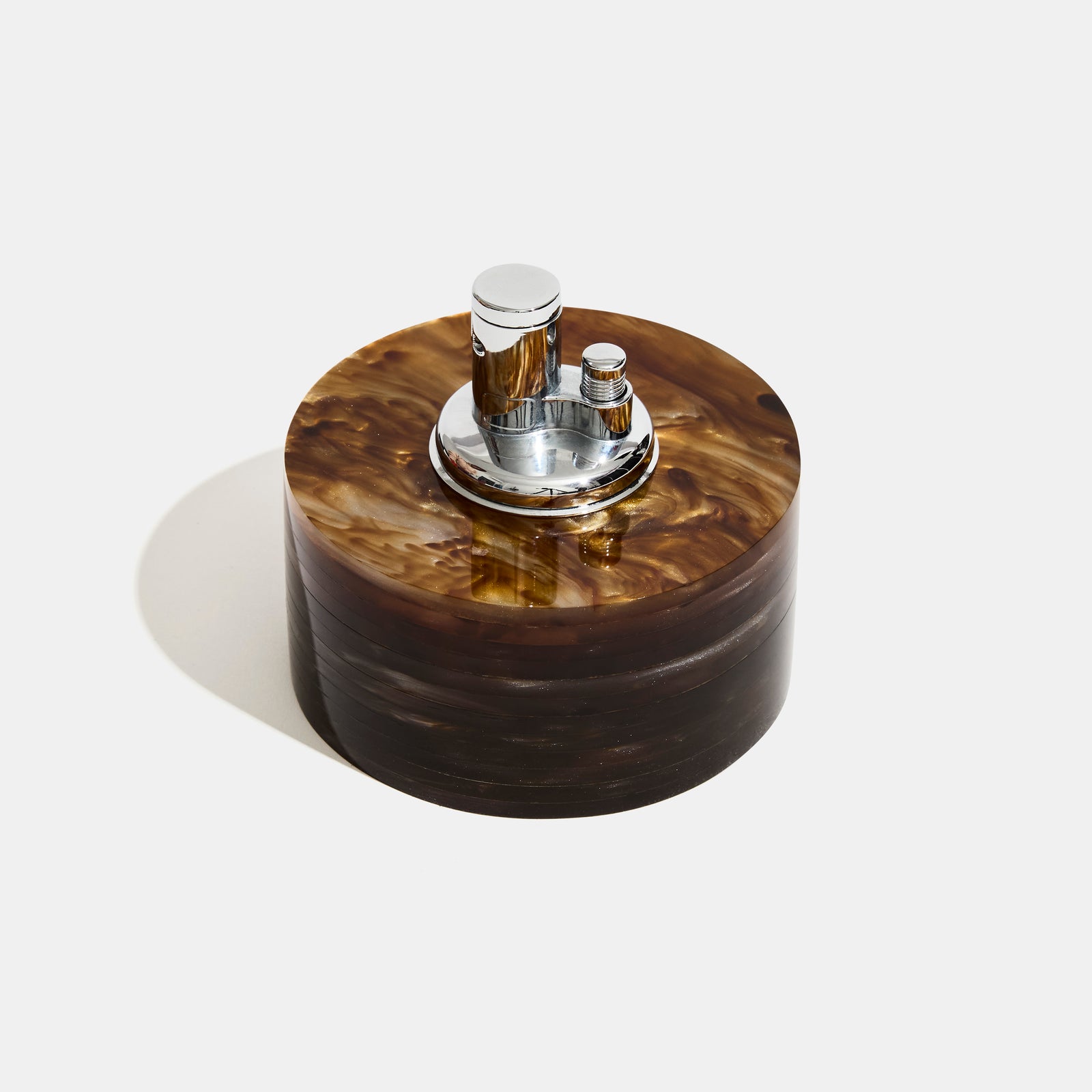 Round acrylic lighter container with silver metallic top on a white background